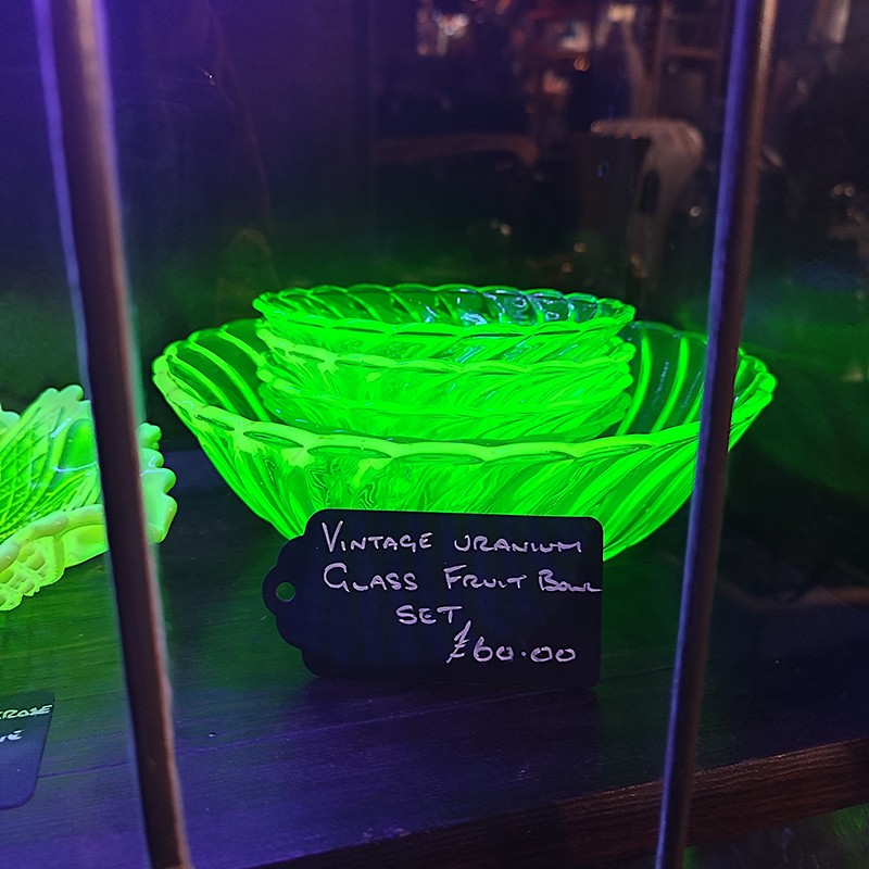 closeup of a fruit bowl made of uranium glass, glowing under a blacklight
